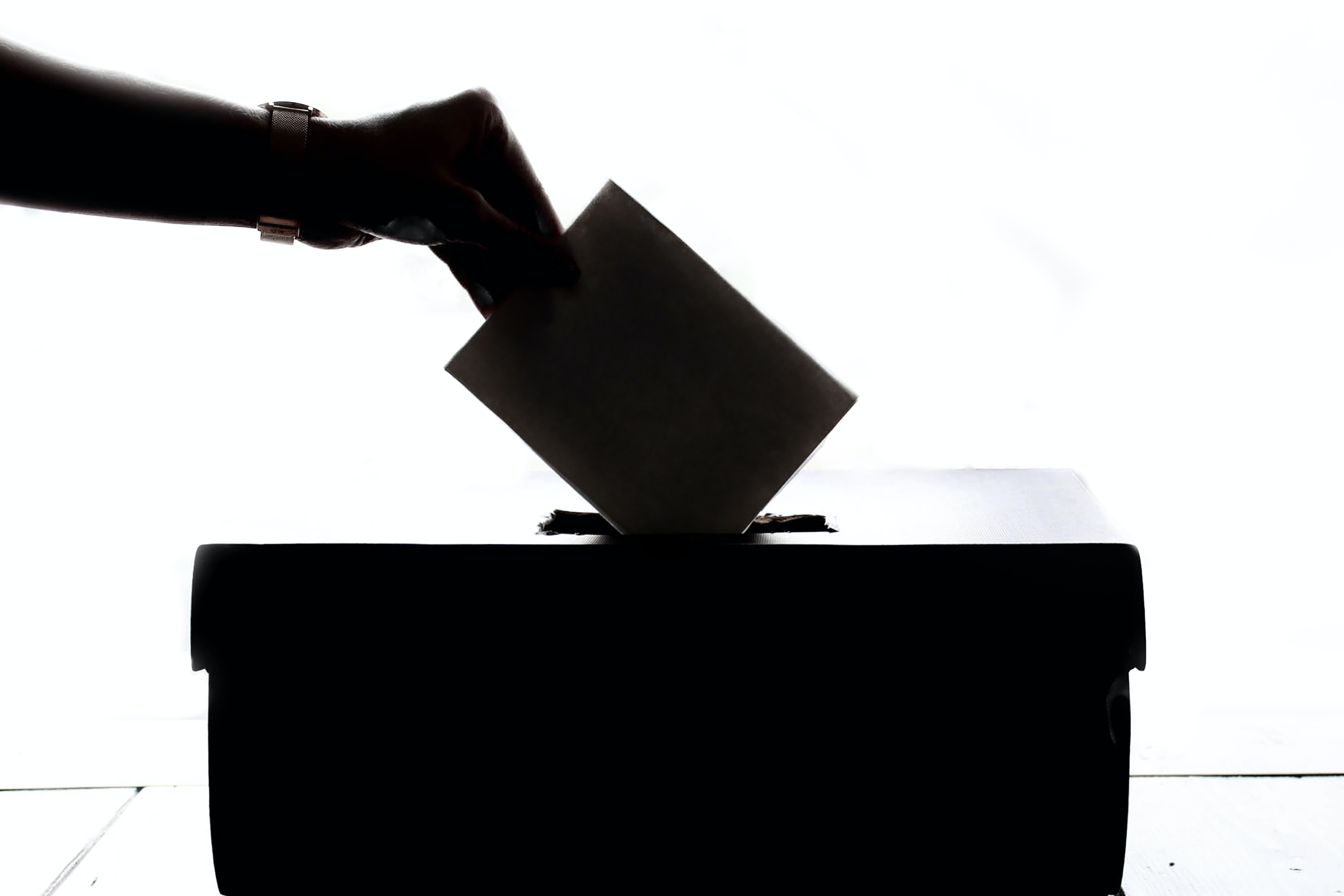 A hand posting a ballot paper into a ballot box